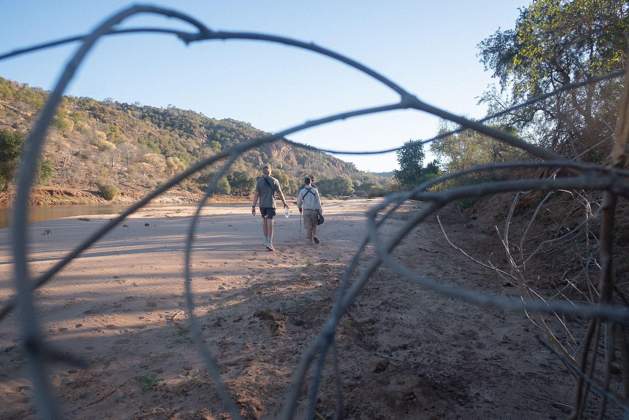 Walkers crossing a wide sandy riverbed