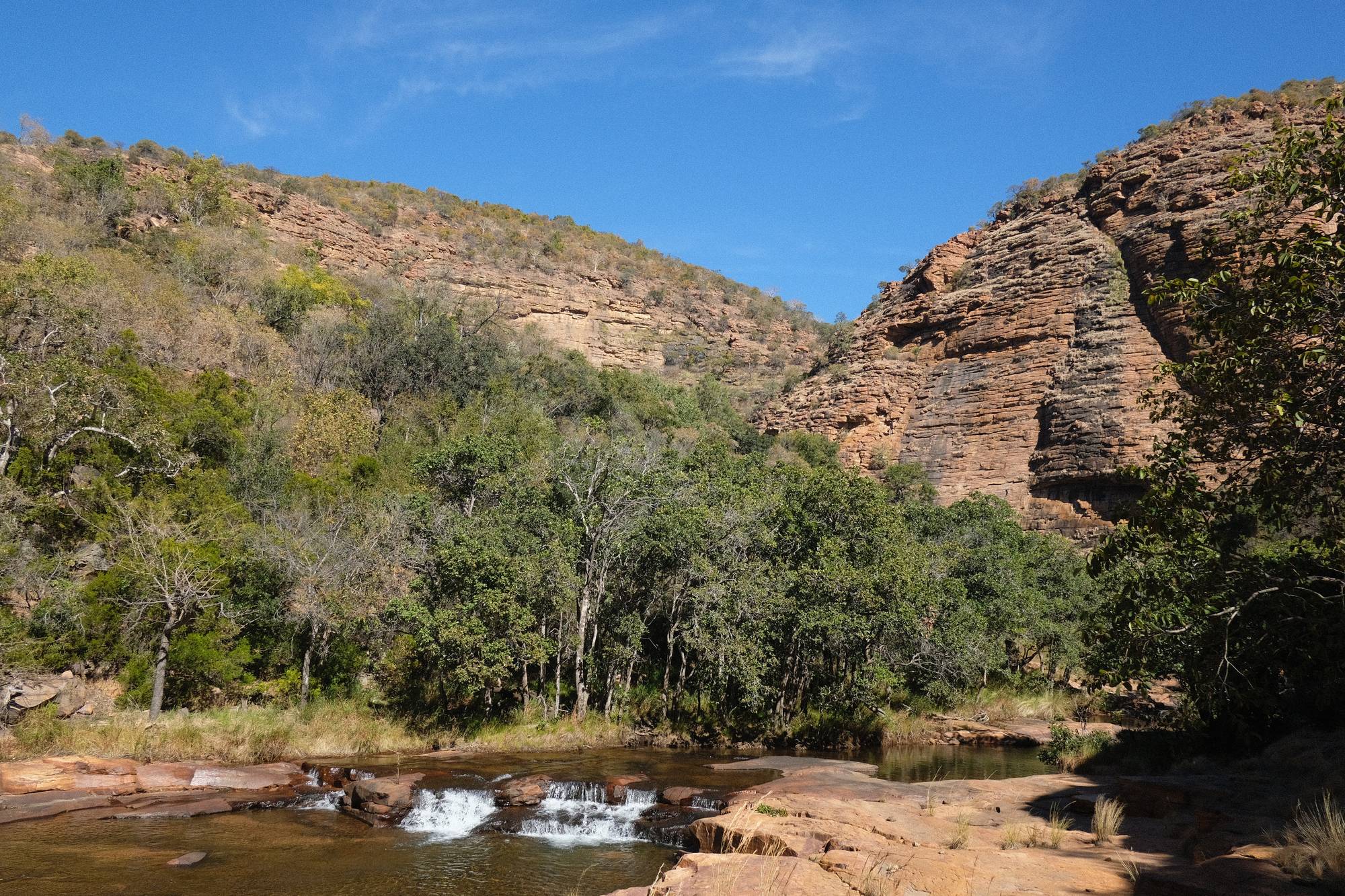 A river cascade beneath red cliffs